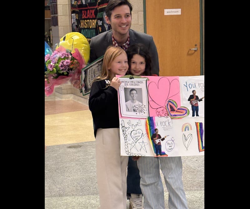 Teacher Joshua Lerner poses with two of his students