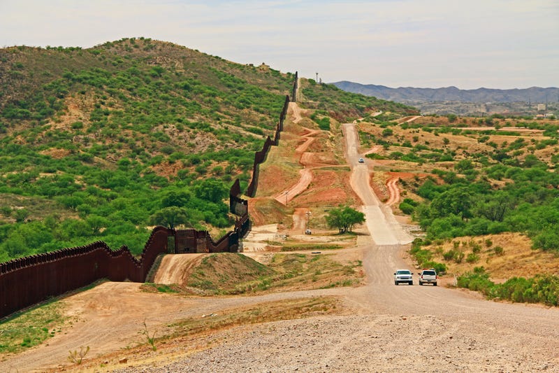 The border wall beside a road near Nogales, Arizona separating the United States from Mexico with border patrol vehicle