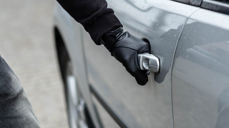 Car thief hand pulling the handle of a car - stock photo