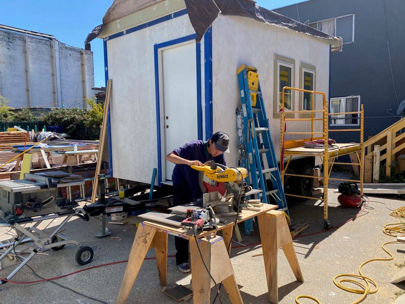A volunteer helps construct a tiny house for homeless youth.