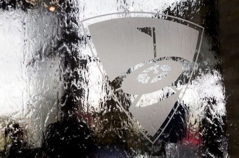 The TopGolf logo, seen from the back side of a glass water wall. 