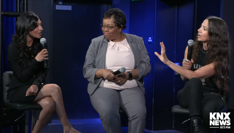 three women sitting onstage in a heated discussion