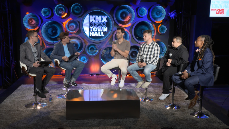 six people sitting onstage during panel
