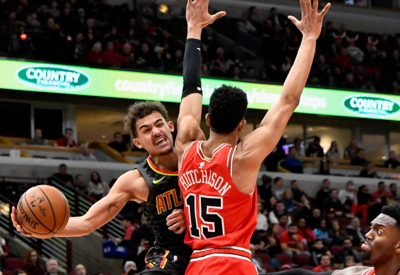 Hawks guard Trae Young (11) passes the ball around Bulls forward Chandler Hutchison (15). 