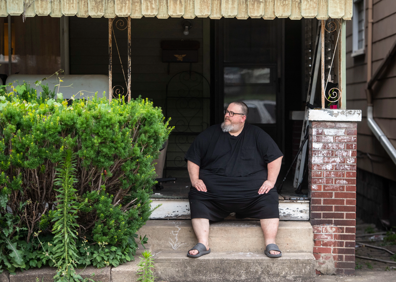 Mike Ramsey sits on the front porch of his house.