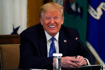 President Donald Trump smiles as he holds a debit card handed to him by Treasury Secretary Steven Mnuchin that will be used to send payments by the Treasury Department during a Cabinet Meeting in the East Room of the White House. (AP Photo/Evan Vucci)