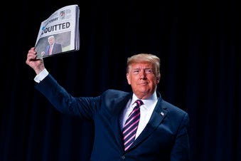 President Donald Trump holds up a newspaper with a headline that reads "ACQUITTED" during the 68th annual National Prayer Breakfast, at the Washington Hilton, Thursday, Feb. 6, 2020, in Washington. (AP Photo/ Evan Vucci)