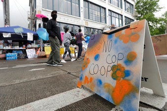 People walk near what is being called the "No Cop Co-op" were protesters and others can get free food and other supplies, Thursday, June 11, 2020, inside what is being called the "Capitol Hill Autonomous Zone" in Seattle. (AP Photo/Ted S. Warren)