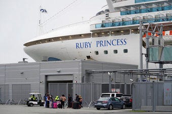 People stand on a pier outside the Ruby Princess cruise ship and wait to be picked up in San Francisco, Thursday, Jan. 6, 2021. The U.S. Centers for Disease Control and Prevention is investigating a cruise ship that docked in San Francisco on Thursday after a dozen vaccinated passengers tested positive for coronavirus.