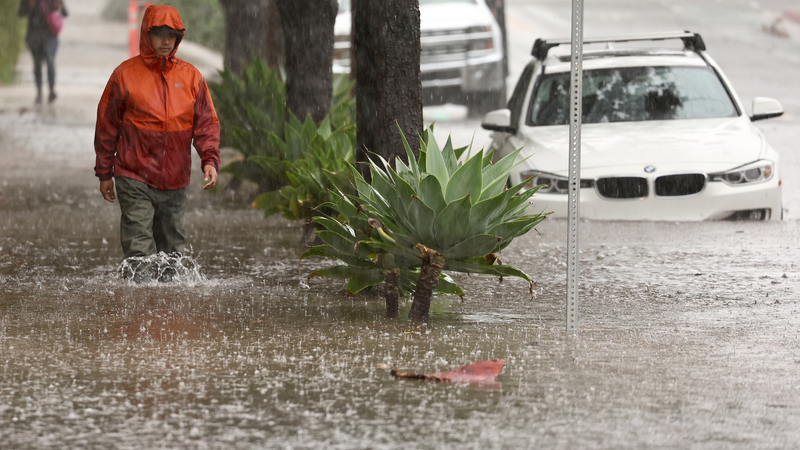 A person walks through flood waters as a powerful long-duration atmospheric river storm, the second in less than a week, impacts California on February 4, 2024 in Santa Barbara, California. The storm is delivering potential for widespread flooding, landslides and power outages while dropping heavy rain and snow across the region.