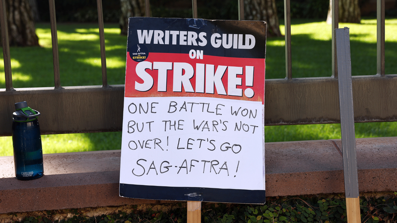 BURBANK, CALIFORNIA - SEPTEMBER 26: A WGA support sign rests near SAG-AFTRA members picketing outside Warner Bros. Studio as the actors strike continues on September 26, 2023 in Burbank, California. Hollywood is awaiting the final vote on a tentative contract agreement between over 11,000 Writers Guild of America (WGA) members and Hollywood studios in the nearly 150-day writers strike.