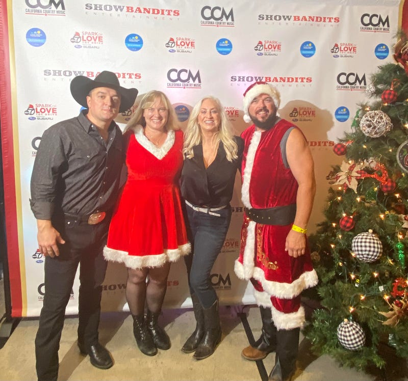 K-Frog's Pepper with Showbandits Founders Daniel Bonte and Tina Shultz, and Volunteer Geremy in front of a step and repeat banner and Christmas tree at Cali Country Christmas in 2023