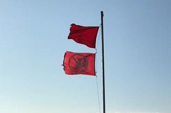Double red flags flying above beach