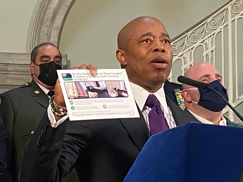 Mayor Adams holds up the brochure detailing services that the city is passing out to homeless people