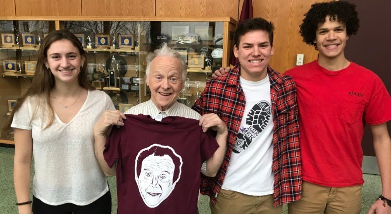 John “Woody” McGoldrick (second from left) poses with his shirt and students, (from left) senior Becca Gable, freshman Ethan Weilheimer, and senior Josiah Campbell.