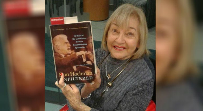 Gloria Hochman holding the book "Stan Hochman Unfiltered: 50 Years of Wit and Wisdom from the Groundbreaking Sportswriter." 