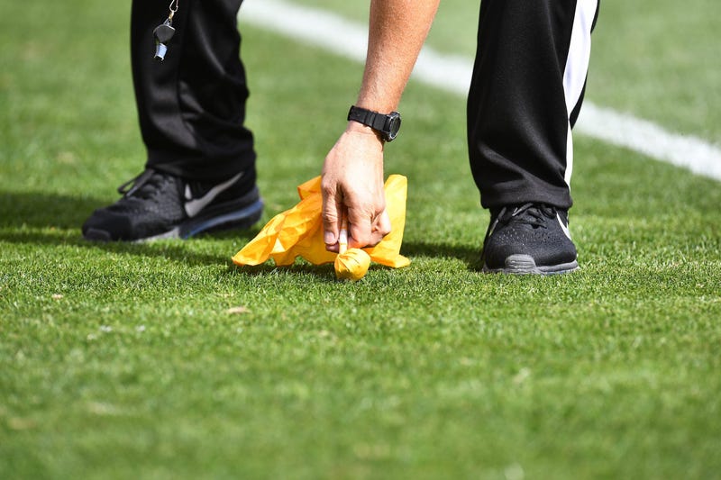 NFL referee picking up a penalty flag