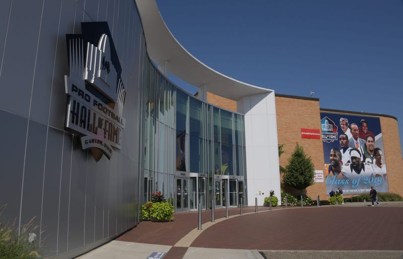 A banner featuring 2019 inductees Champ Bailey and Pat Bowlen and Gil Brandt and Tony Gonzalez and Ty Law and Kevin Mawae and Ed Reed and Johnny Robinson hangs outside the Pro Football Hall of Fame.