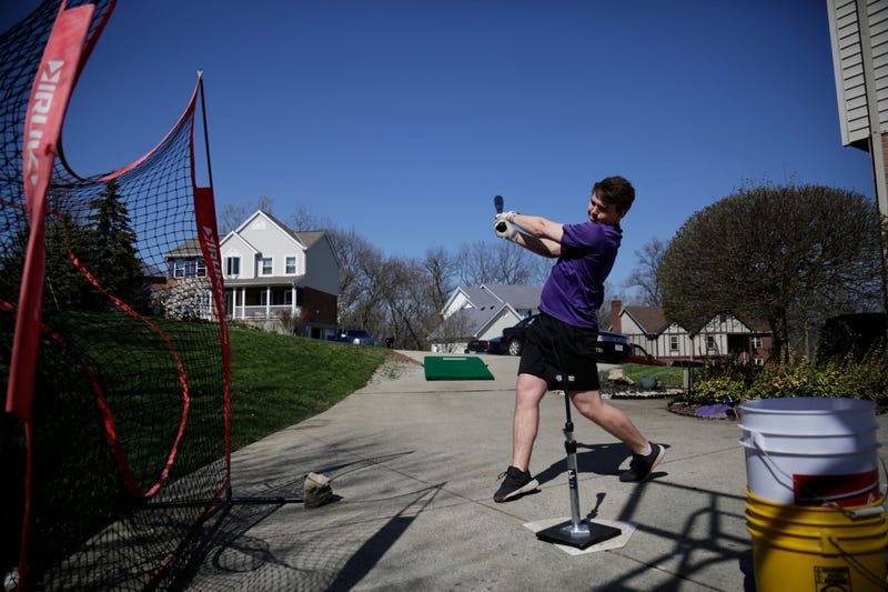 Kory Klingenbeck, a senior at Elder High School, practices hitting off a tee in his parents' driveway in Delhi Township, Ohio, on Wednesday, March 25, 2020. With schools closed, the Klingenbeck brother have attempted to continue workouts together at their