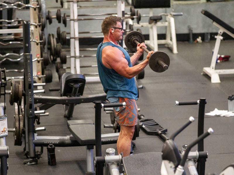A man lifts a barbell as he works out while being socially distant from others at Momentum Fitness. Gyms Reopening