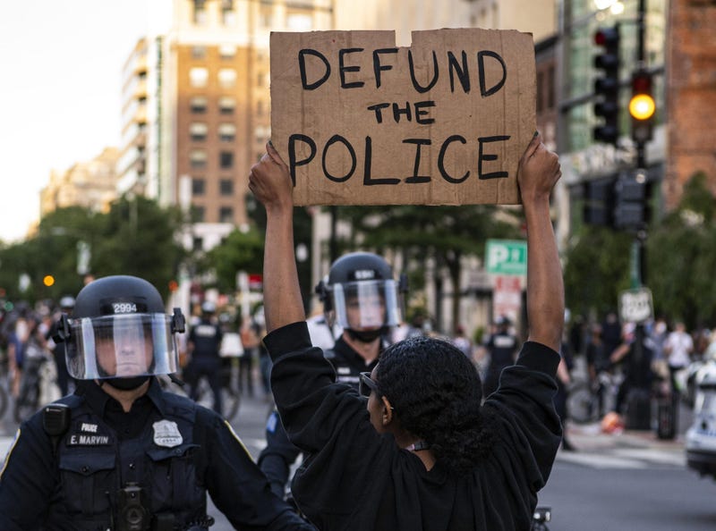 Protester holding Defund the police sign