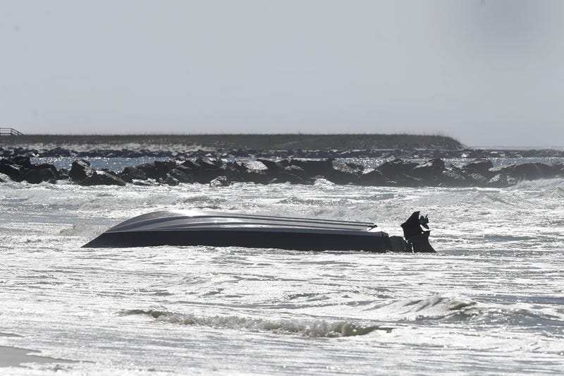 An approximately 20-foot center-console boat sits upside down in the surf near the west jetty on Okaloosa Island Monday morning. Destin Fire Rescue responded about 7:40 a.m. Monday to a distress call of a capsized boat with three passengers, all of whom a