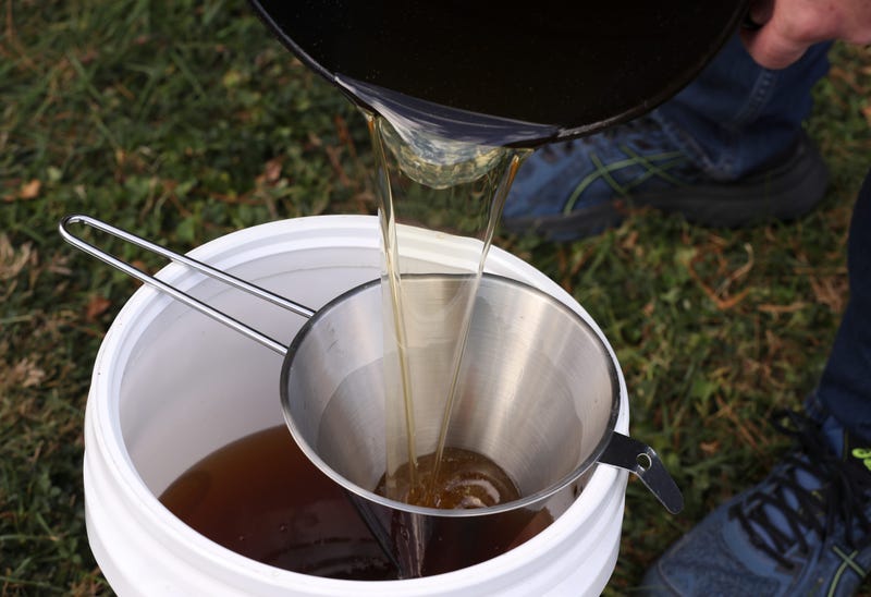Todd Bluechel pours cooled used cooking oil into a container after he deep fried a turkey in his backyard in Louisville, Ky. on Nov. 8, 2020. Bluechel is the v.p. of sales marketing business development for Oil-Tech, a company that recylcles used cooking