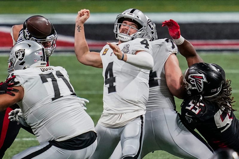 Atlanta Falcons defensive tackle Jacob Tuioti-Mariner (rear left) strips the ball away from Las Vegas Raiders quarterback Derek Carr