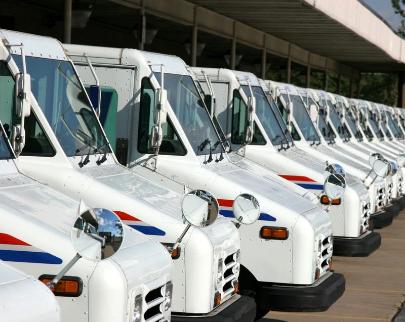 the front ends of USPS delivery trucks, lined up