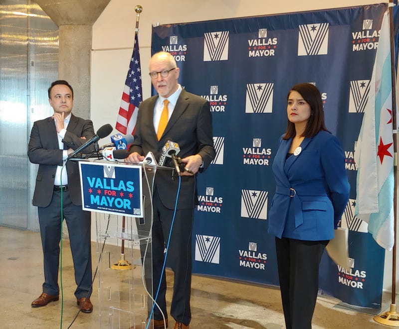 Vallas at lectern, with two officials
