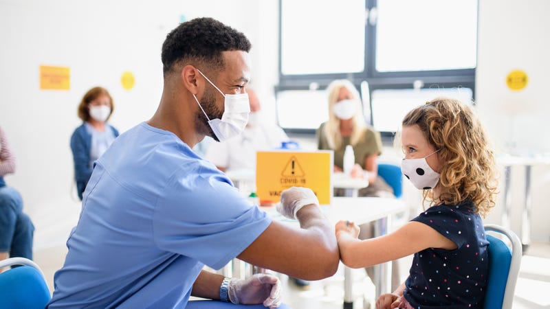 A child receives an elbow bump from a nurse following a covid vaccination