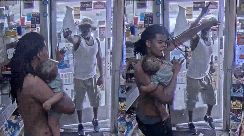 man throws up his arm to protect himself and the baby he is holding from an armed suspect