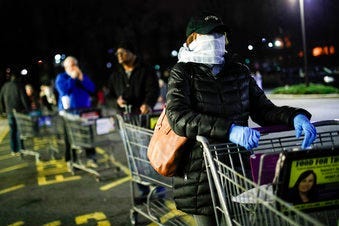 Customers wearing protective masks and gloves wait in line at a Stop & Shop supermarket that opened special morning hours to serve people 60-years and older due to coronavirus concerns. (AP Photo/John Minchillo)