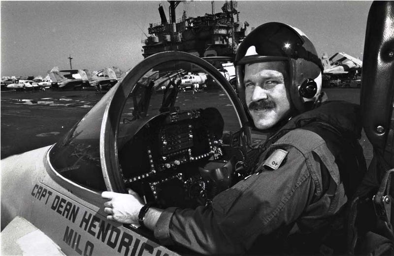 Mark Fox poses in a Hornet with the USS Saratoga in the background a few days after his battle with an Iraqi MiG. Photo courtesy of Fox.