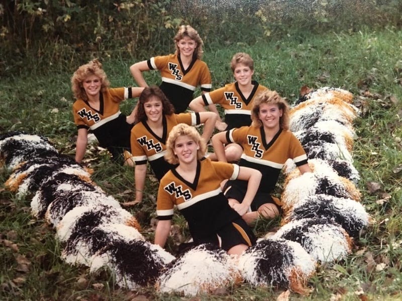 6 High School Cheerleaders Sitting In Formation With Pom-pons