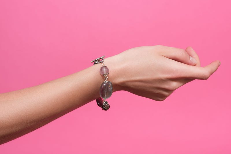 A woman's wrist on a pink background