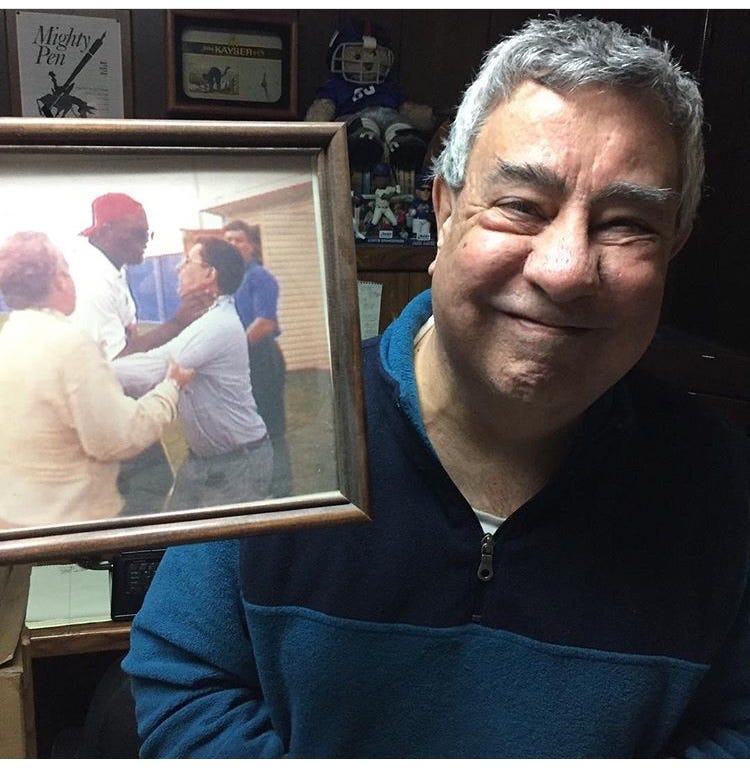 Ernie Palladino poses with a photo of Lawrence Taylor choking him. 
