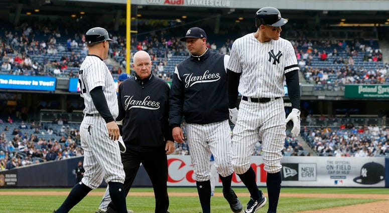 The Yankees' Aaron Judge is checked on by bench coach Josh Bard, trainer Steve Donohue and first-base coach Reggie Willits prior to leaving a game against the Kansas City Royals in the sixth inning at Yankee Stadium on April 20, 2019.