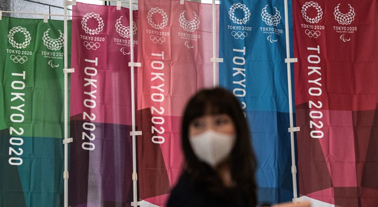 A woman walks past Tokyo 2020 Olympics banners on March 19, 2020 in Tokyo.