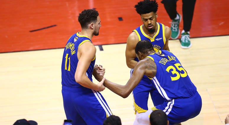 Kevin Durant (35) is helped to his feet by Klay Thompson (11) and Quinn Cook of the Golden State Warriors after sustaining an injury against the Raptors in Game 5 of the 2019 NBA Finals on June 10, 2019, at Scotiabank Arena in Toronto, Canada. 